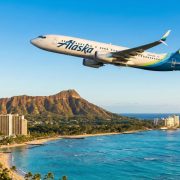An Alaska Airlines Boeing 737 jet flying over Waikiki Beach and the Diamond Head volcanic cone in Honolulu, Hawaii.